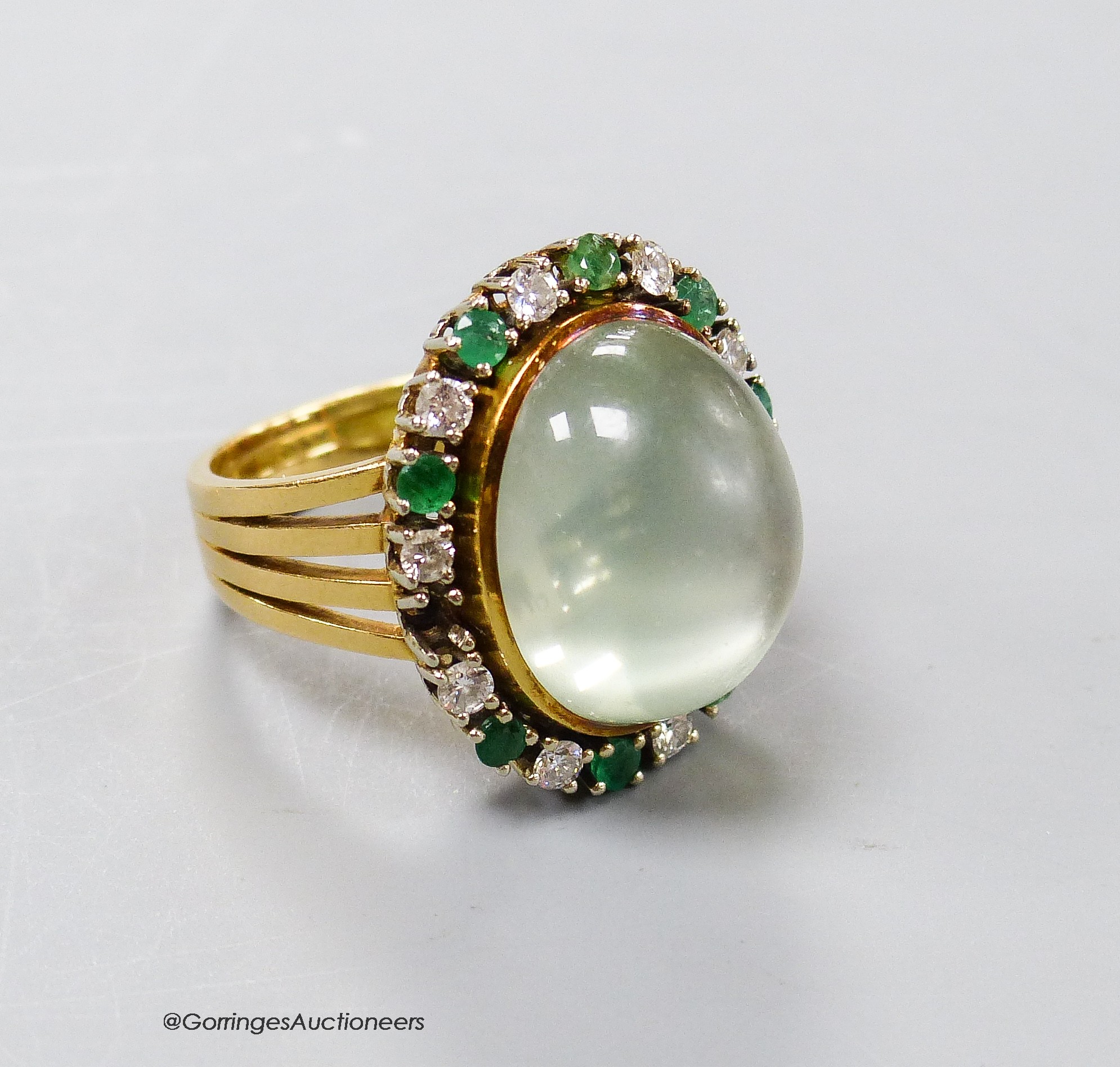 A modern 750 yellow metal, pale green cabochon stone, emerald and diamond set oval dress ring, size N, gross 14 grams.